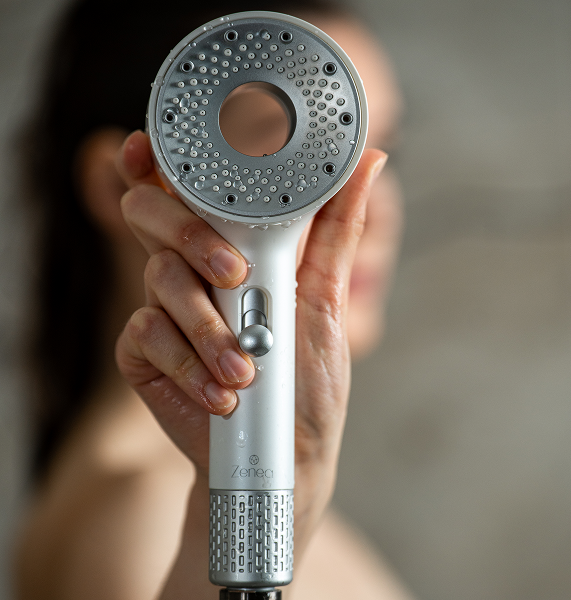 Modelka drží filtračnú sprchovú hlavicu Zenea v ruke